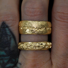 Load image into Gallery viewer, The Canyon ring (top) with the Forest Guardian ring (bottom); the top ring is wider with a river channel and &quot;rocks&quot;. The bottom ring features a raised branch on top of the band with a forest texture all over the band.